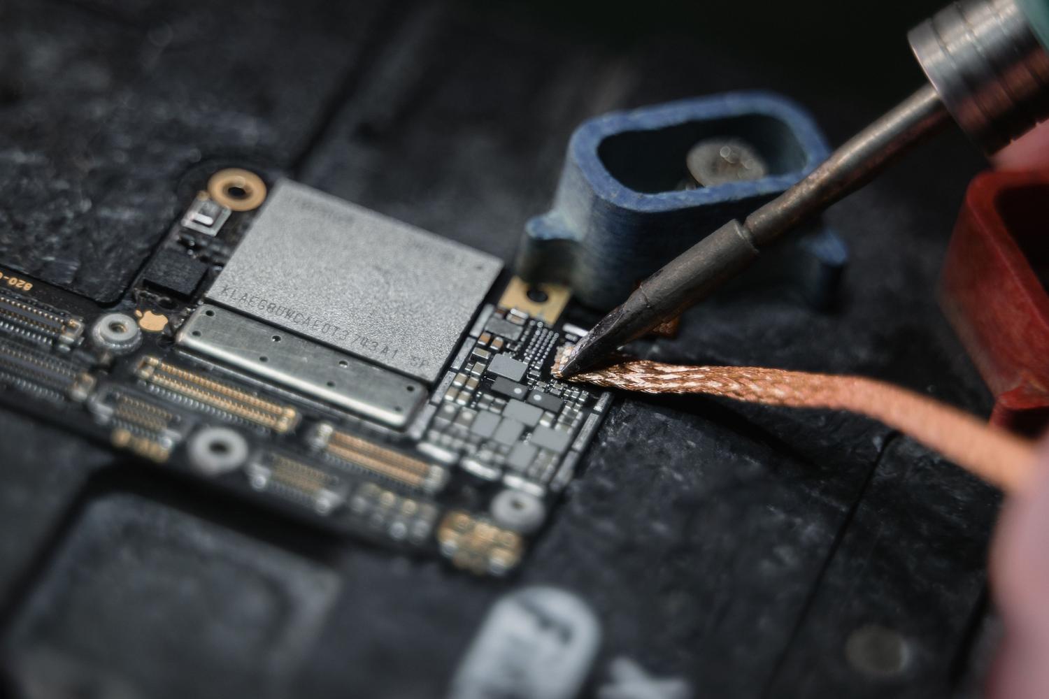 Técnico realizando una soldadura en la placa base de un dispositivo, representando la reparación especializada de audio.
