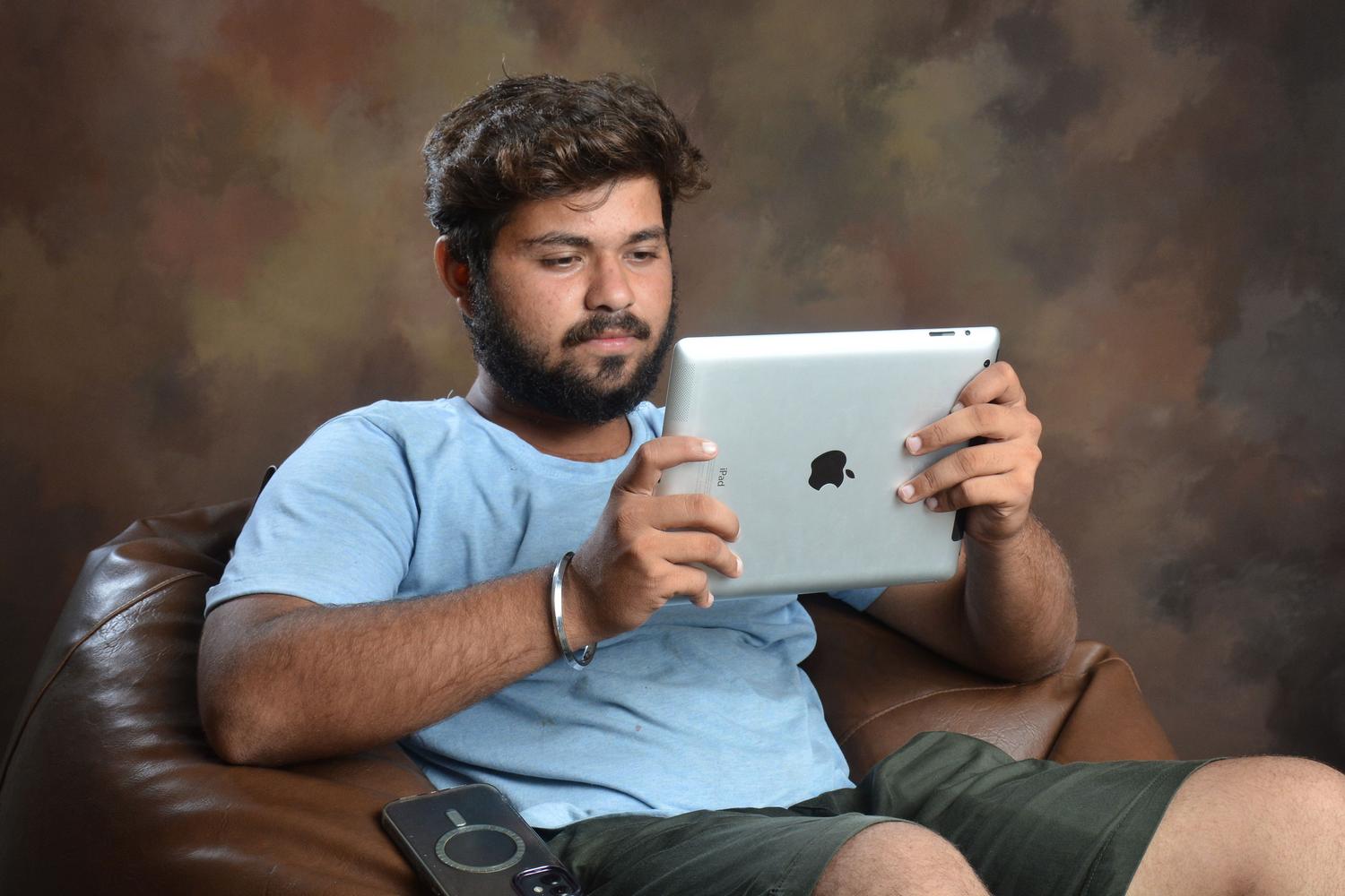 Hombre joven utilizando una tablet en un entorno relajado, representando la fluidez de la experiencia de usuario y conectividad.
