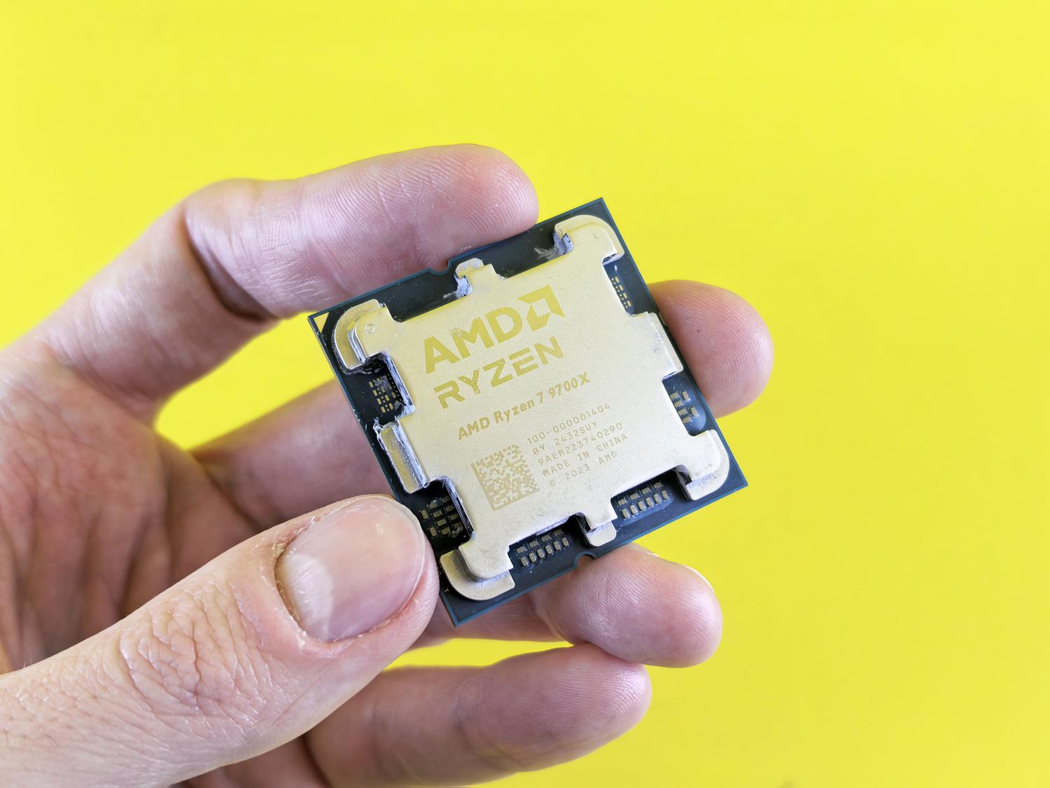 Primer plano de un procesador AMD Ryzen 7 sostenido en una mano, representando la arquitectura y potencia del hardware.