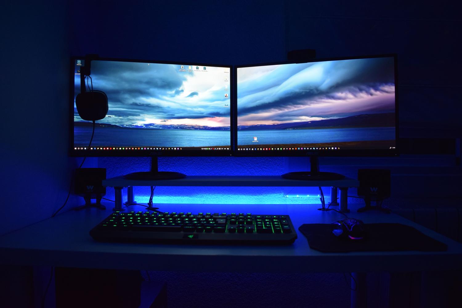Configuración de monitores duales con iluminación ambiental RGB, ideal para ilustrar el ajuste de brillo mediante paneles de control de NVIDIA o AMD.
