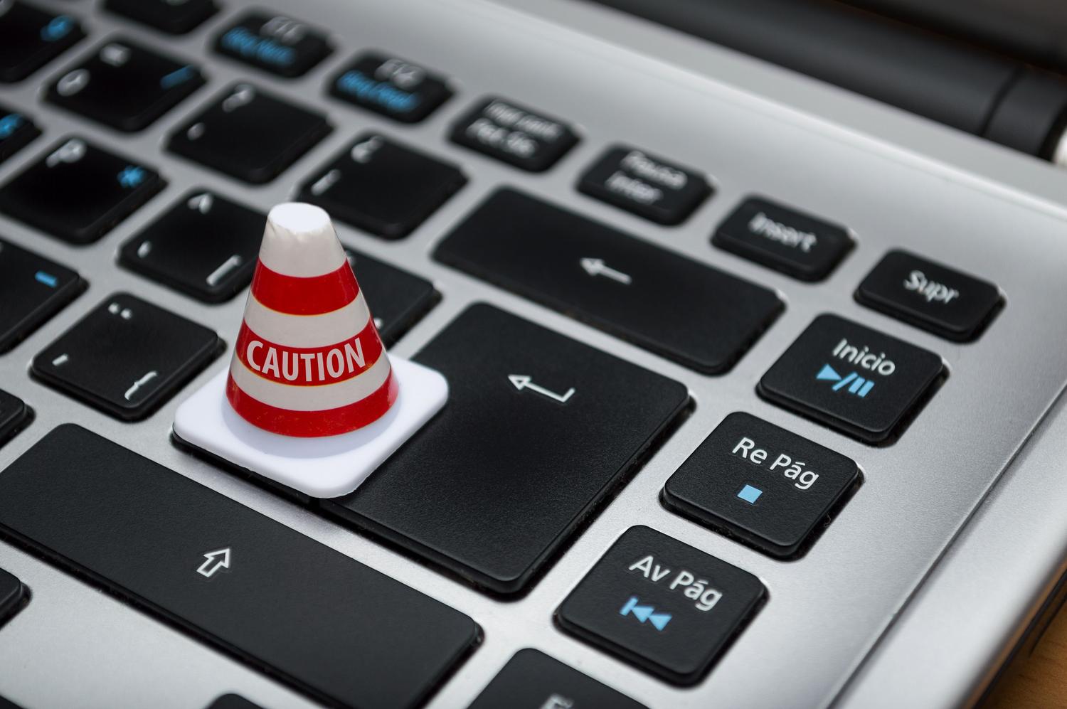 Miniatura de un cono de precaución sobre un teclado de ordenador, simbolizando el riesgo de desactivar las defensas del sistema.