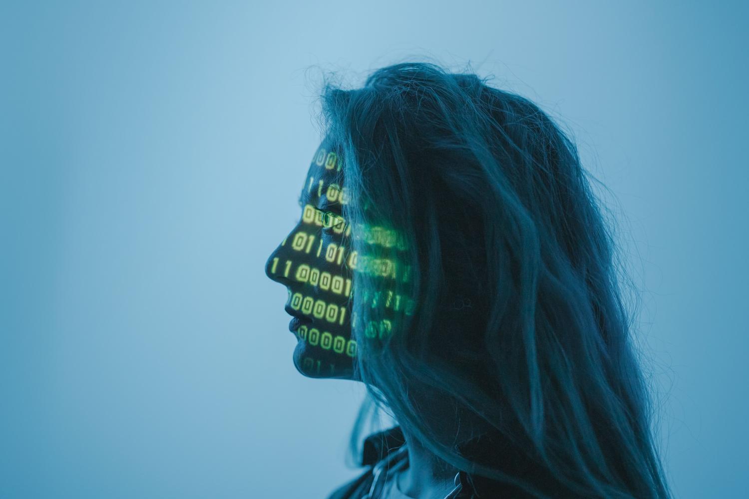 Concepto visual de IA y ciberseguridad con código binario proyectado sobre un rostro.