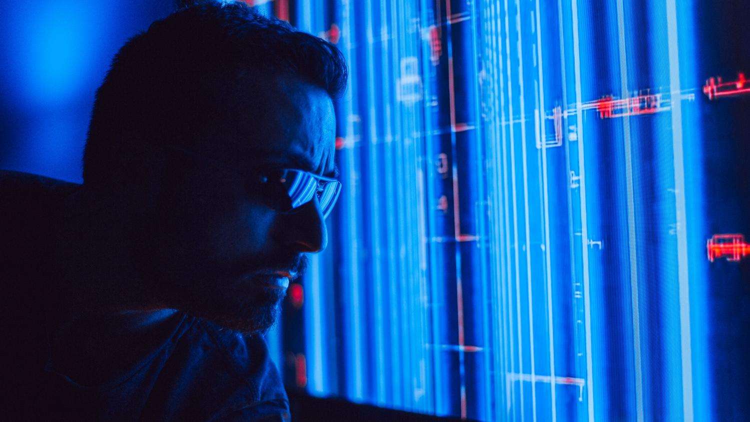 Analista de seguridad monitoreando datos holográficos con alertas rojas, ilustrando la detección de vulnerabilidades por IA.