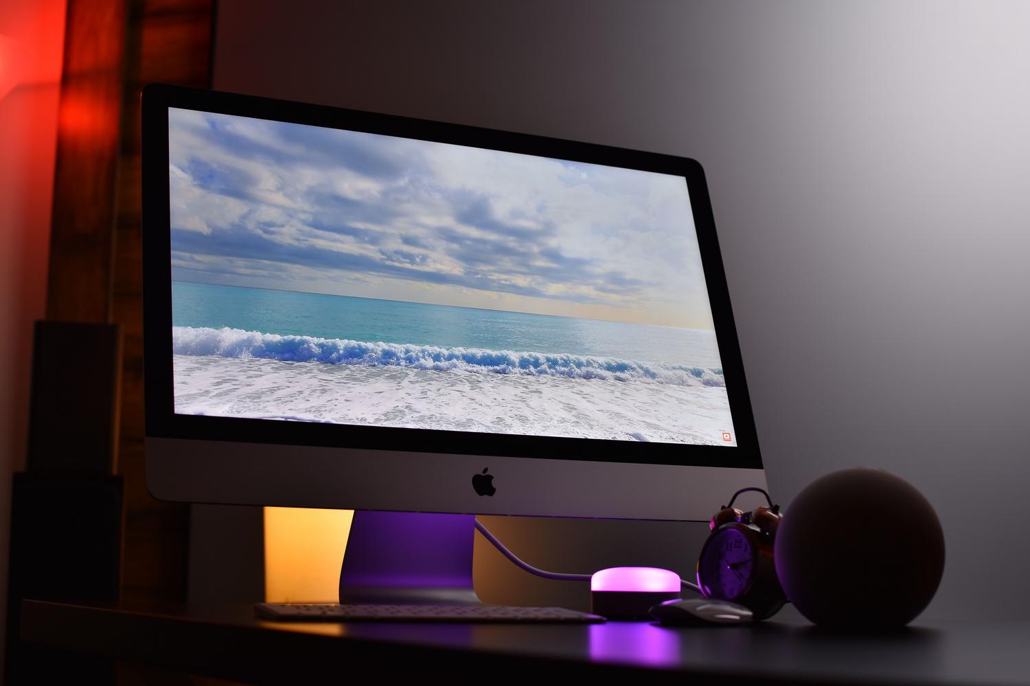 Escritorio moderno con un iMac Apple y luz ambiental, representando un entorno de hardware Apple elegante