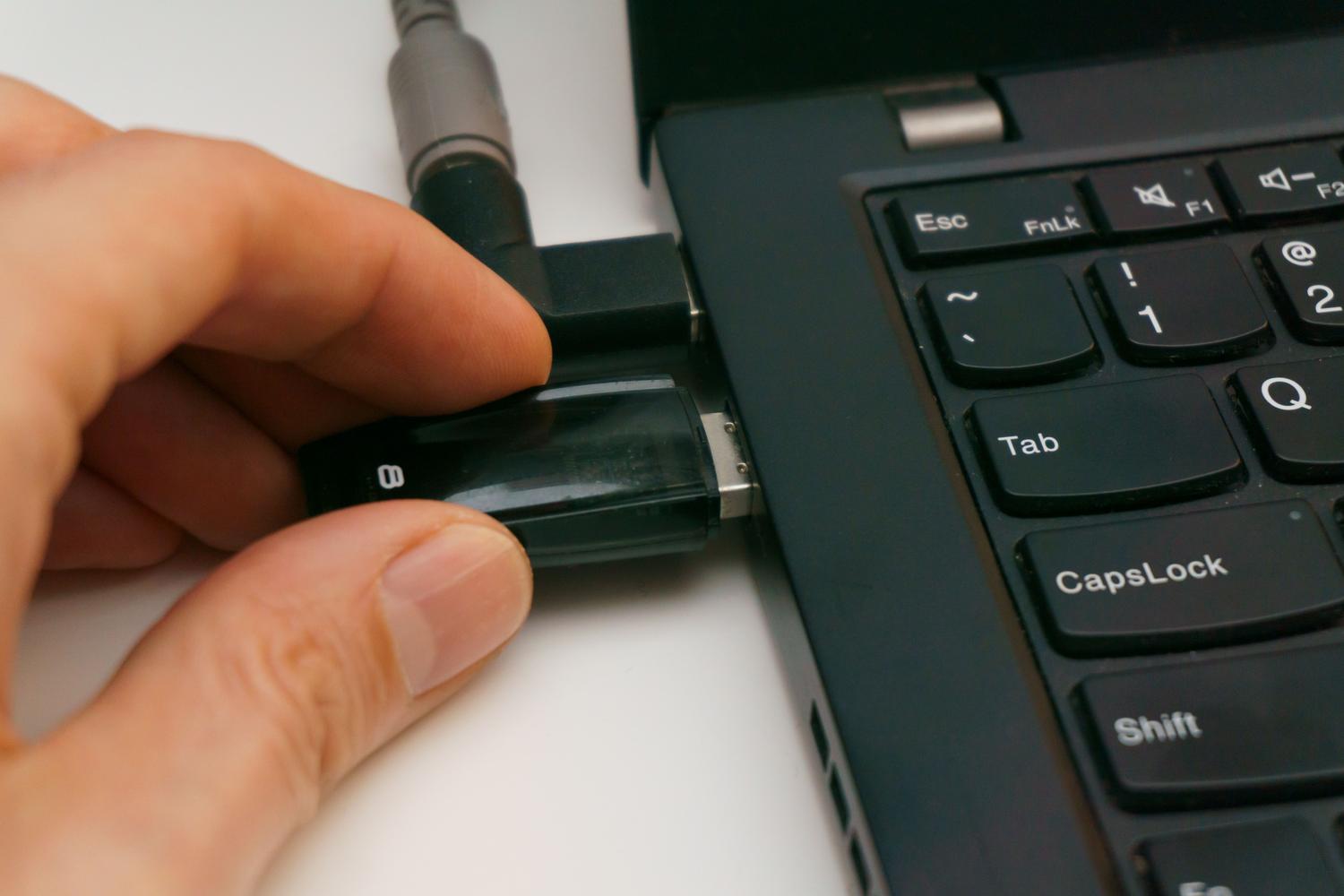 Mano insertando una memoria USB en el puerto de un ordenador portátil para transferir archivos.