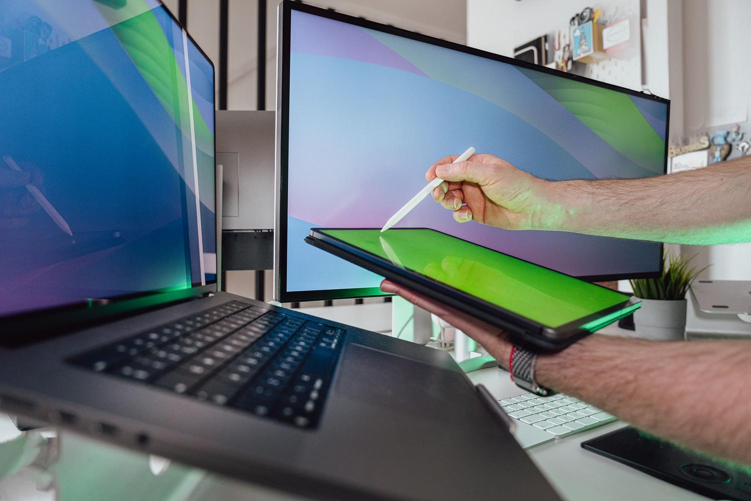 Mano con un lápiz óptico interactuando con una tableta en un entorno tecnológico, demostrando la compatibilidad multidispositivo de los Pointer Events.