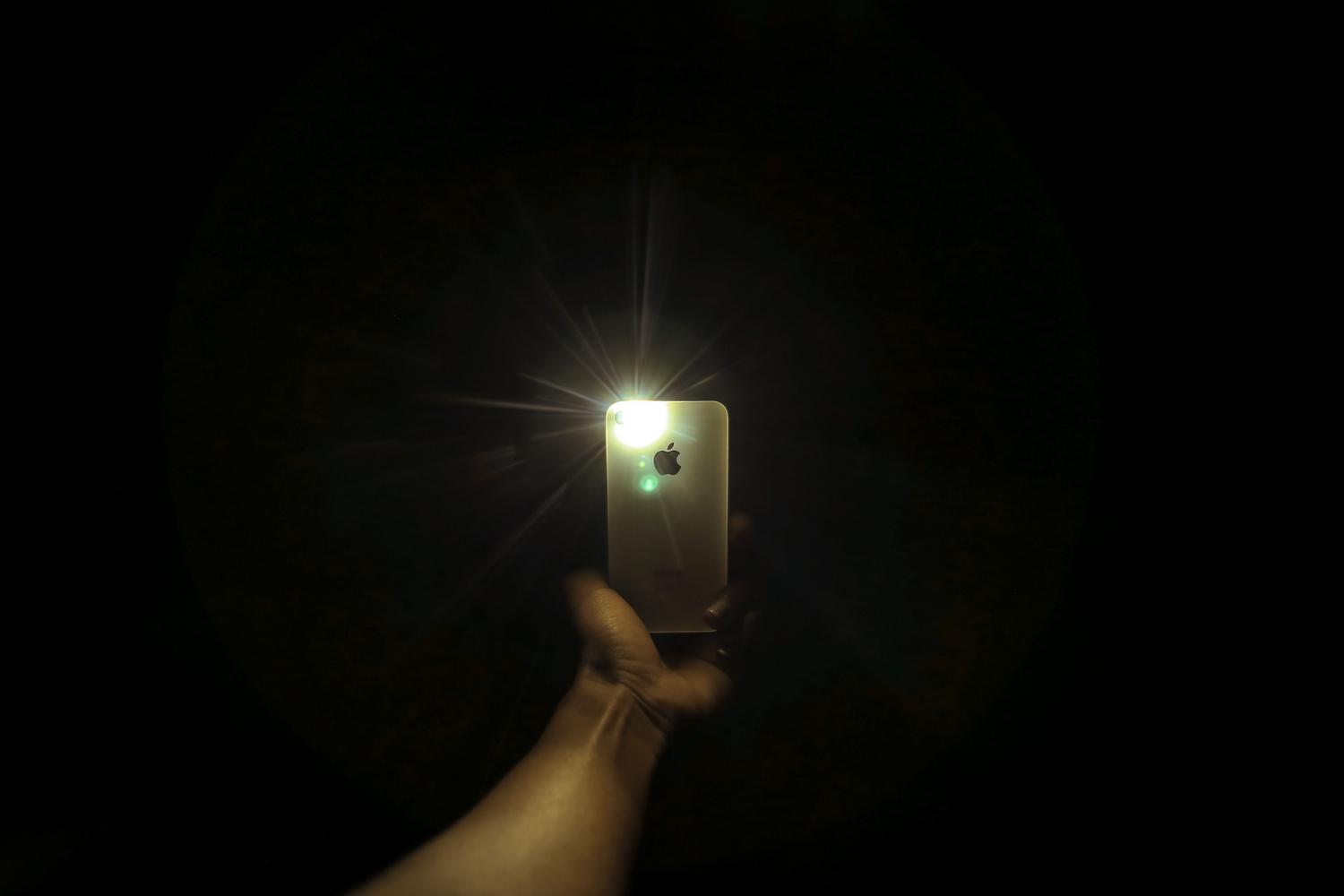 Uso de la linterna de un smartphone en una habitación oscura para ilustrar el efecto de la luz directa
