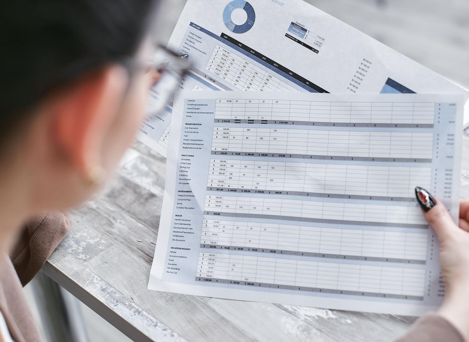 Mujer de negocios revisando hojas de cálculo financieras, representando la aplicación profesional de las funciones de Excel.