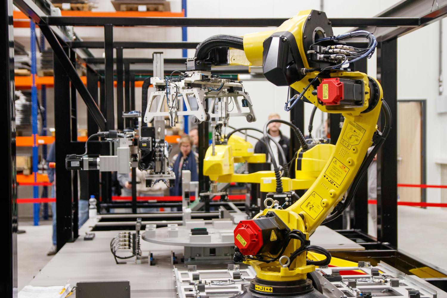 Brazo robótico industrial amarillo trabajando en una fábrica moderna, mostrando la aplicación de la visión artificial en la automatización.