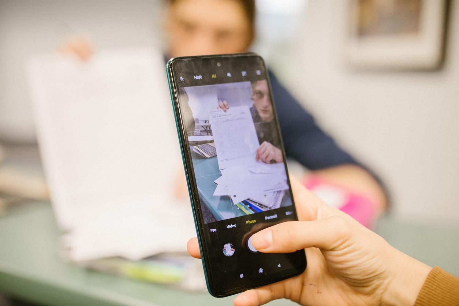 Persona utilizando la cámara de su smartphone para digitalizar documentos, representando el escaneo móvil.