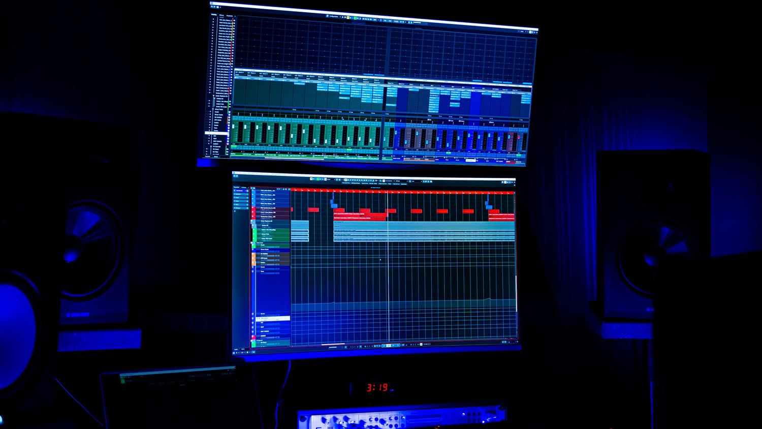 Estudio de grabación moderno con monitores y equipo de audio profesional bajo iluminación azul.