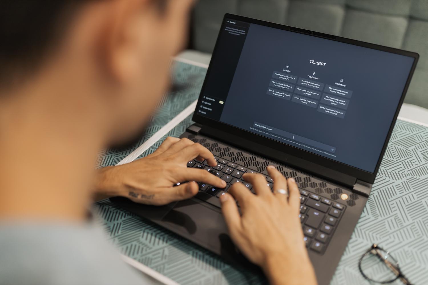 Persona trabajando en un ordenador portátil utilizando herramientas de inteligencia artificial generativa en un entorno profesional y moderno.