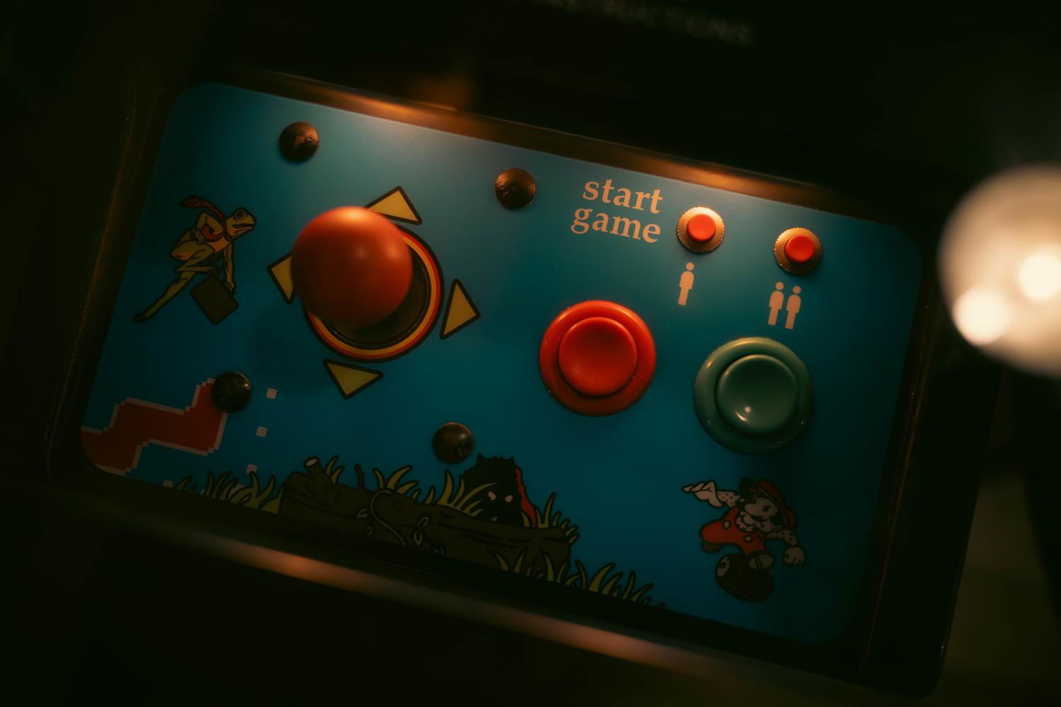 Primer plano de los controles de una máquina recreativa retro con joystick y botones.