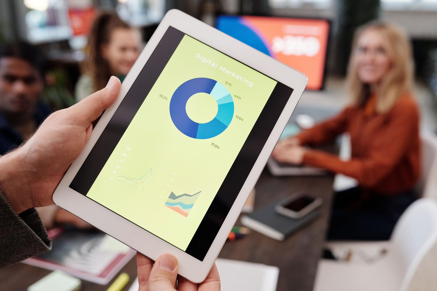 Equipo de profesionales revisando estadísticas de marketing digital en una tablet, representando el análisis de mercado y la toma de decisiones estratégicas.