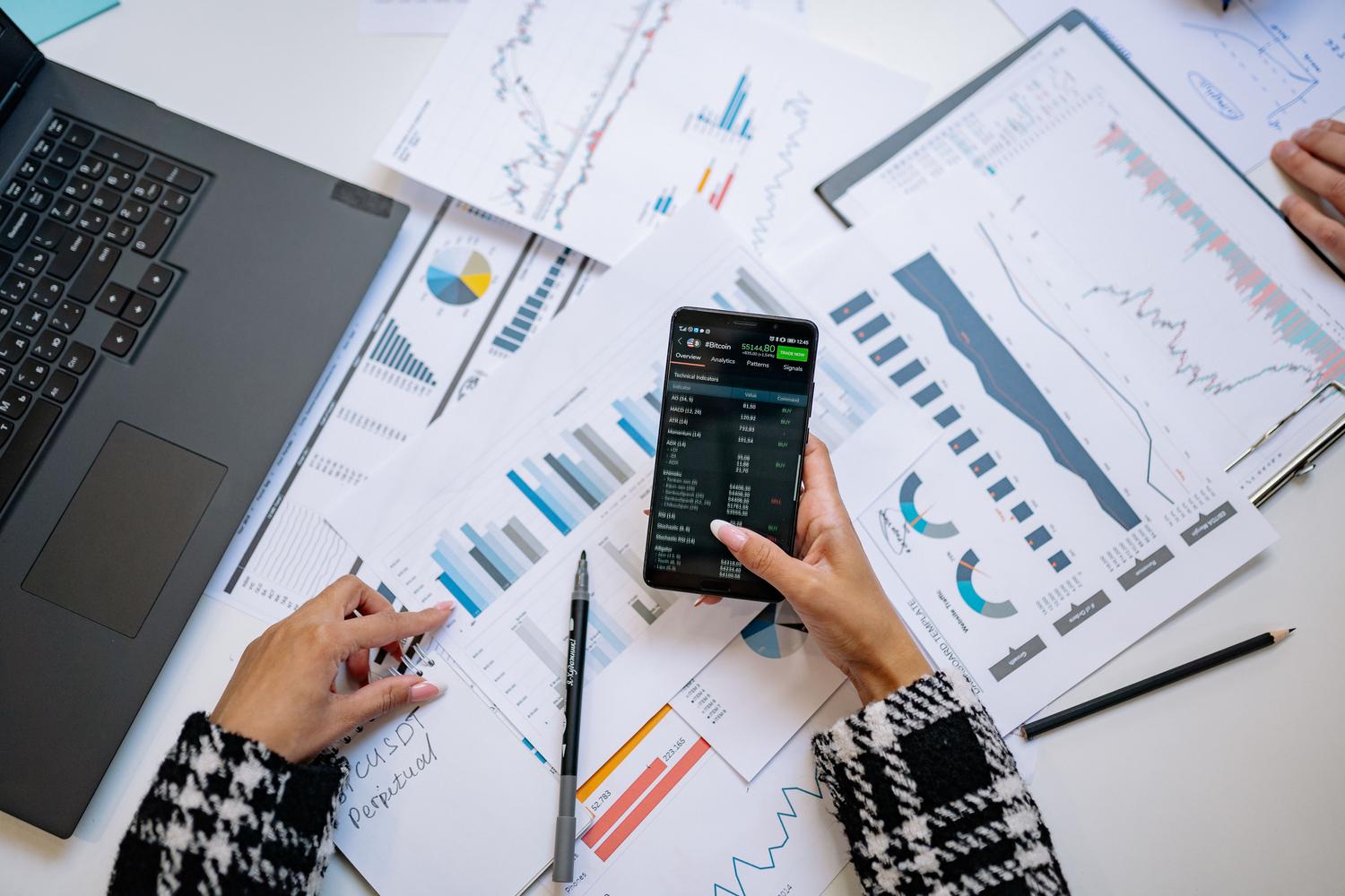 Vista cenital de un espacio de trabajo profesional con un smartphone mostrando datos estructurados y gráficos analíticos, representando el resultado de la extracción de datos.