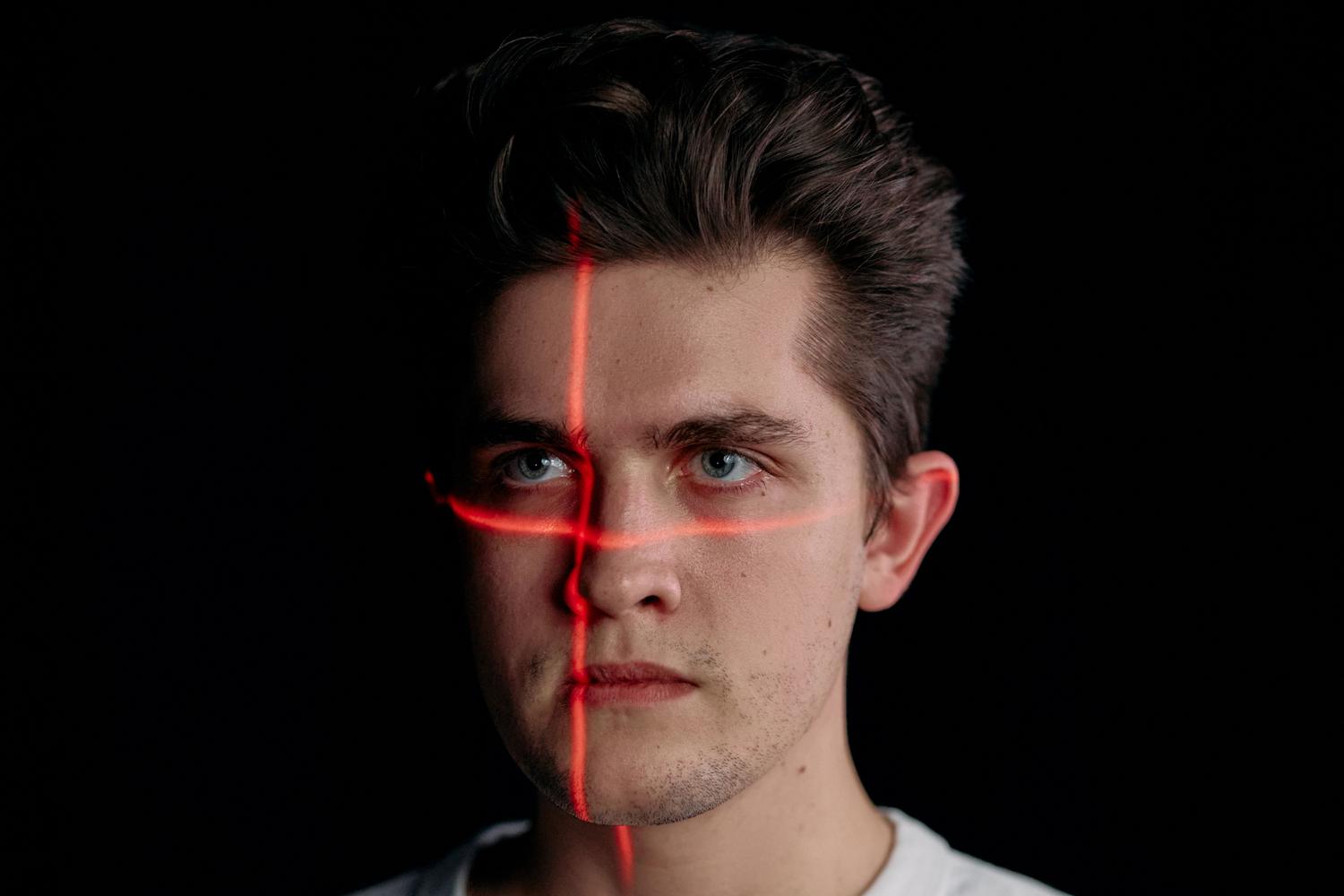 Retrato conceptual de un hombre con líneas de escaneo láser facial, ejemplificando la tecnología de estimación de edad y biometría.