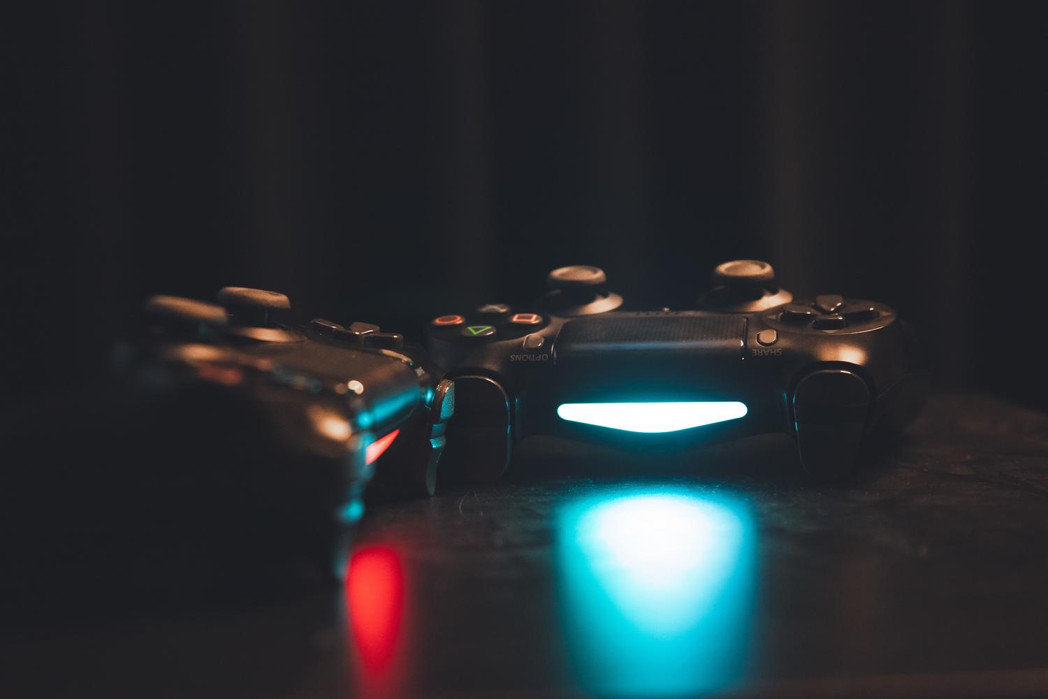 Mandos de videojuegos iluminados sobre una superficie oscura, representando el aspecto competitivo de los videojuegos.