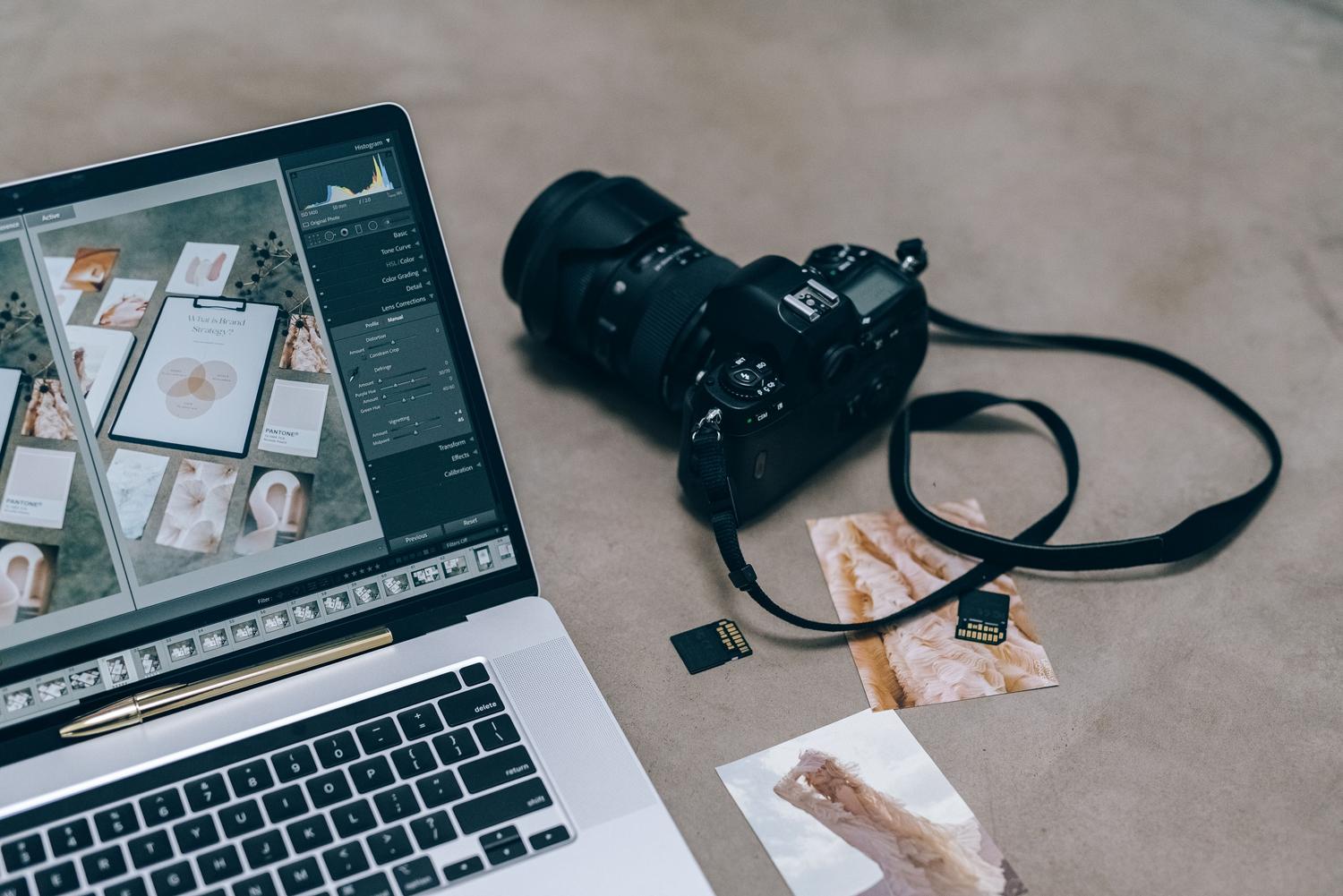 Equipo de fotografía profesional con ordenador portátil y cámara DSLR sobre un escritorio.