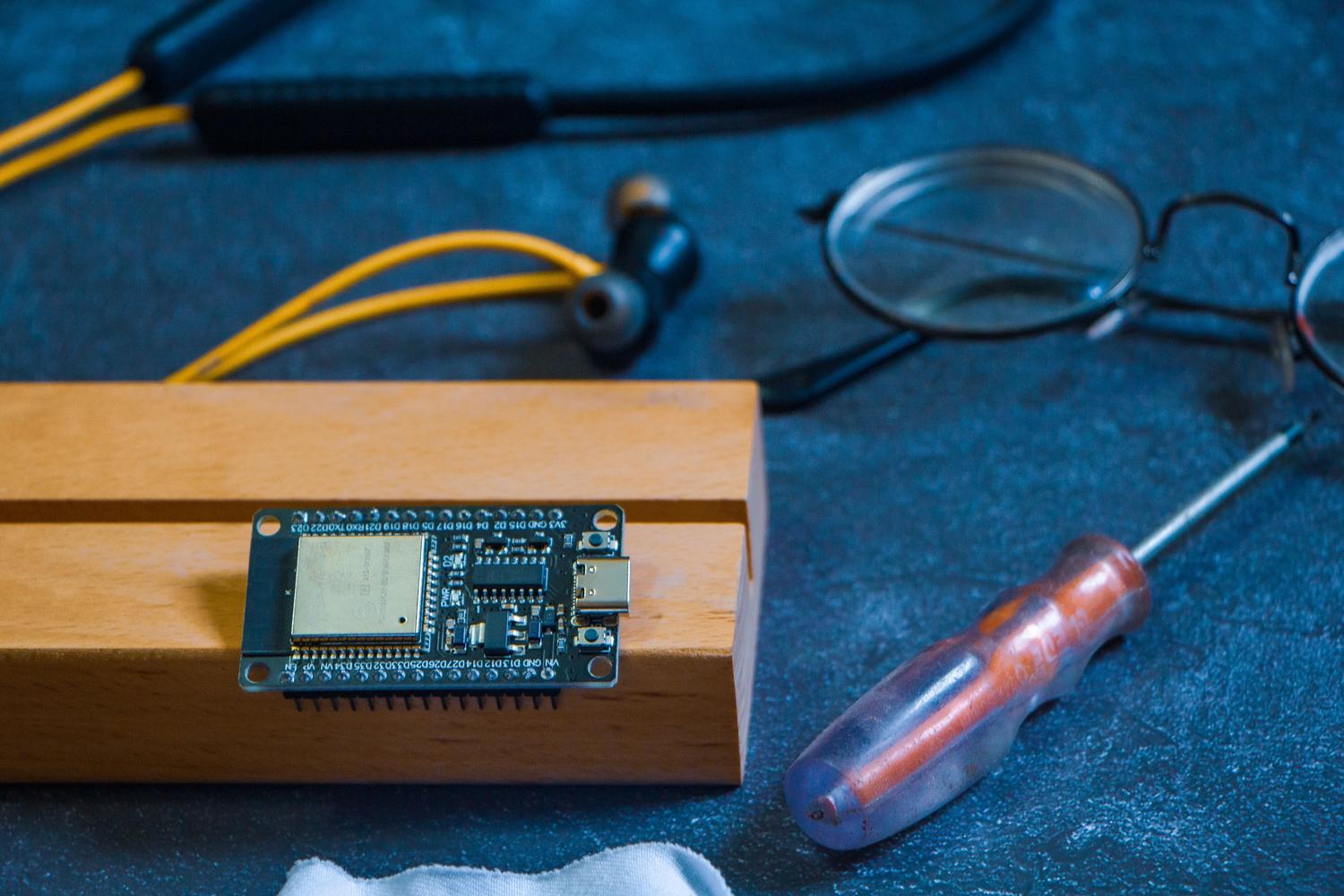 Placa de desarrollo ESP32 sobre un banco de trabajo con herramientas de electrónica, creando una atmósfera de ingeniería y DIY.