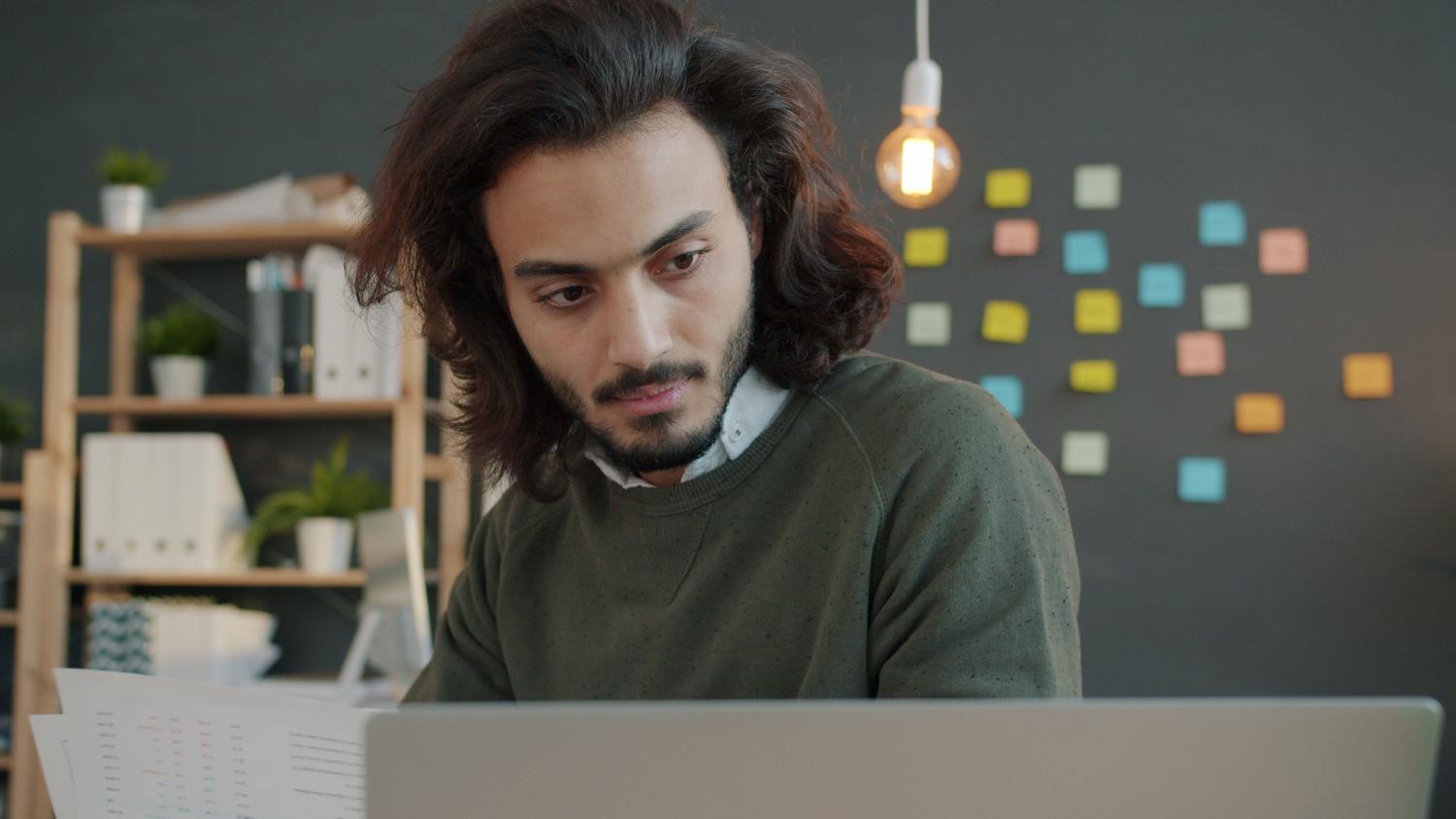 Profesional trabajando concentrado en su oficina en casa con herramientas digitales, representando la productividad y el flujo de trabajo remoto.