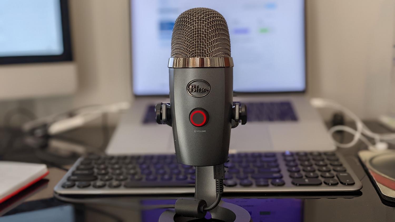 Primer plano de un micrófono profesional Blue Yeti en un escritorio de teletrabajo moderno.