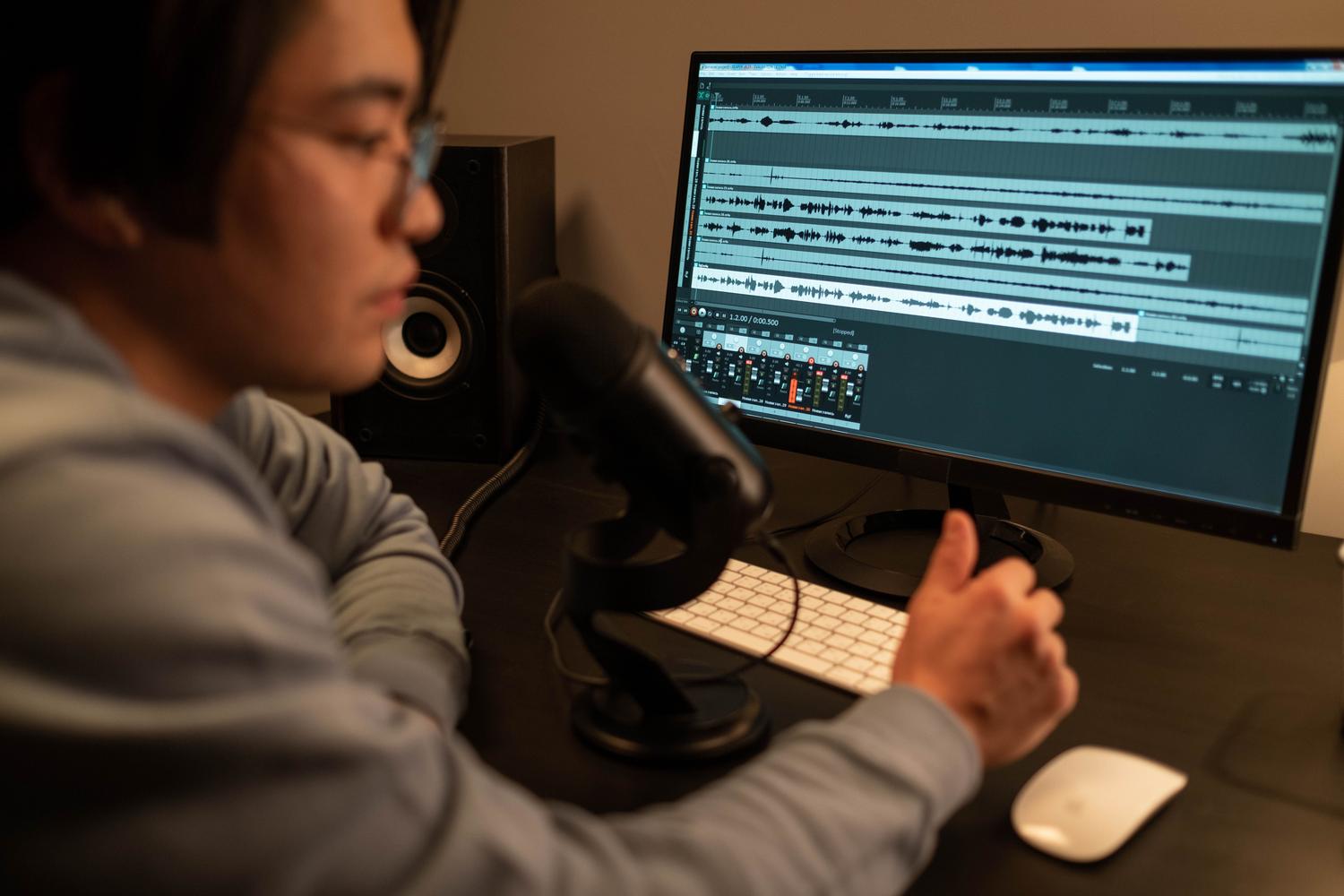 Ingeniero de sonido trabajando en la edición de audio frente a un ordenador en un estudio profesional.
