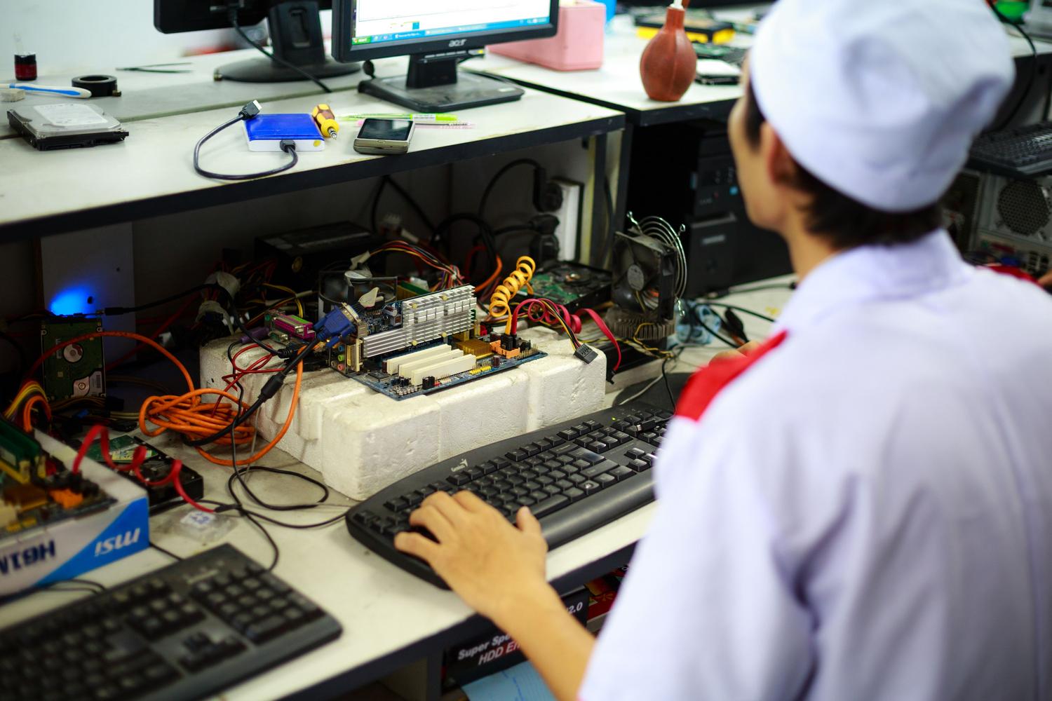 Técnico especializado ensamblando y probando una placa base en un banco de pruebas de laboratorio profesional.