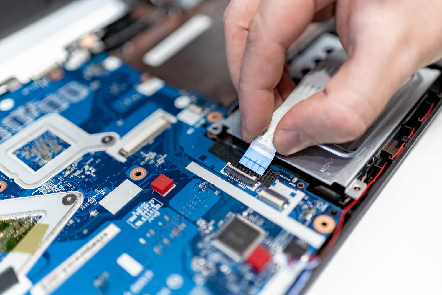 Técnico especializado reparando la placa base de un ordenador portátil, ilustrando el proceso de recuperación técnica.